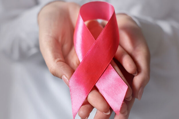 Rožnati trak v ženskih rokah za ozaveščanje o raku dojk, simbolična barva pentlje za ozaveščanje o ljudeh, ki živijo z rakom dojk pri ženskah
