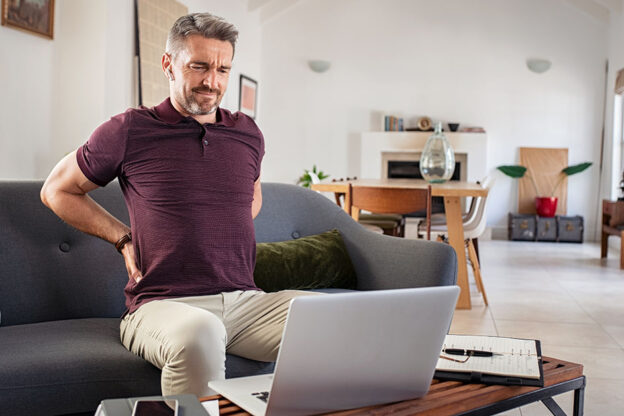 Poslovnež trpi zaradi bolečin v hrbtu med delom na prenosniku.