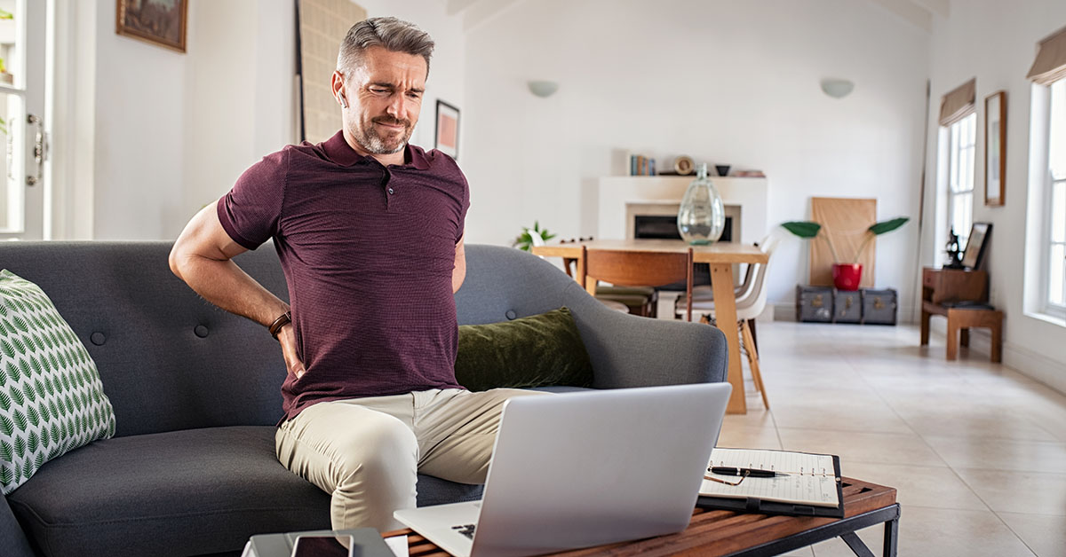 Poslovnež trpi zaradi bolečin v hrbtu med delom na prenosniku.